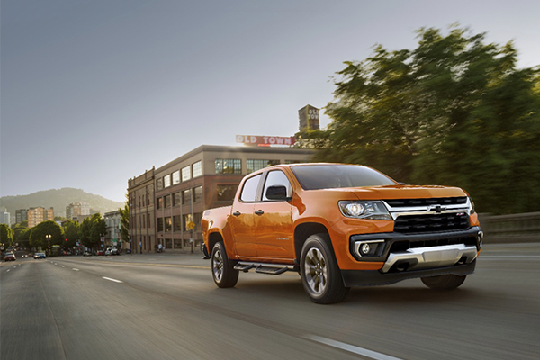 Orange 2021 Chevrolet Colorado driving down a city street. Source: Chevrolet