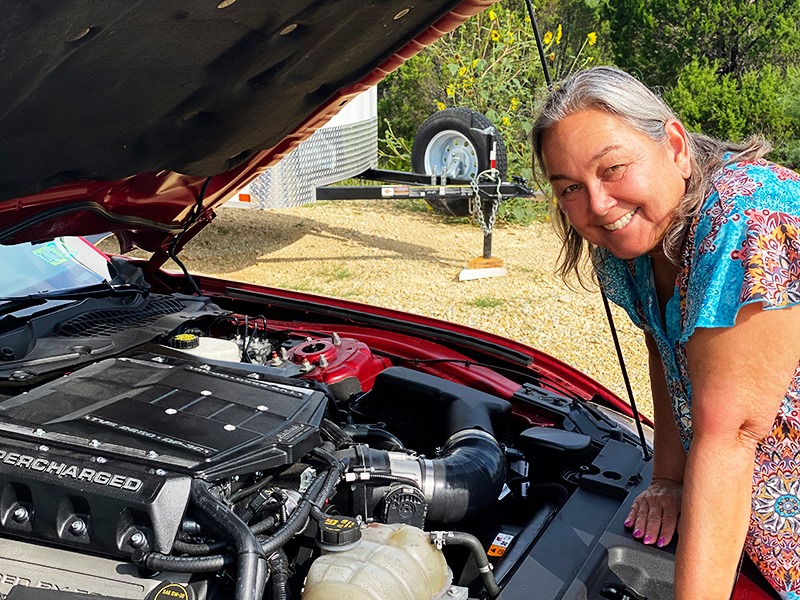 grand prize winner smiling for the camera, standing in front of the raised Mustang GT hood