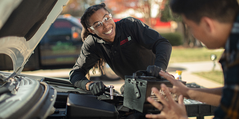 Employee assisting customer with new battery installation