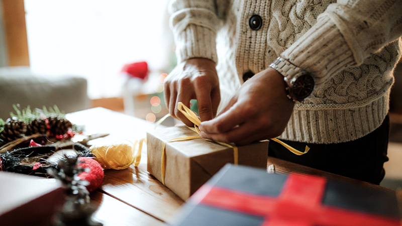 a man tying a bow around a gift he is wrapping