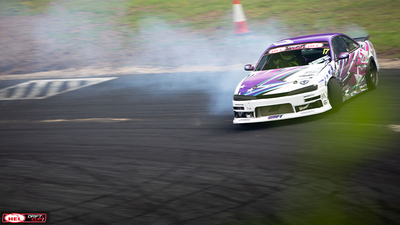 A car drifting sideways on track with smoke from tires