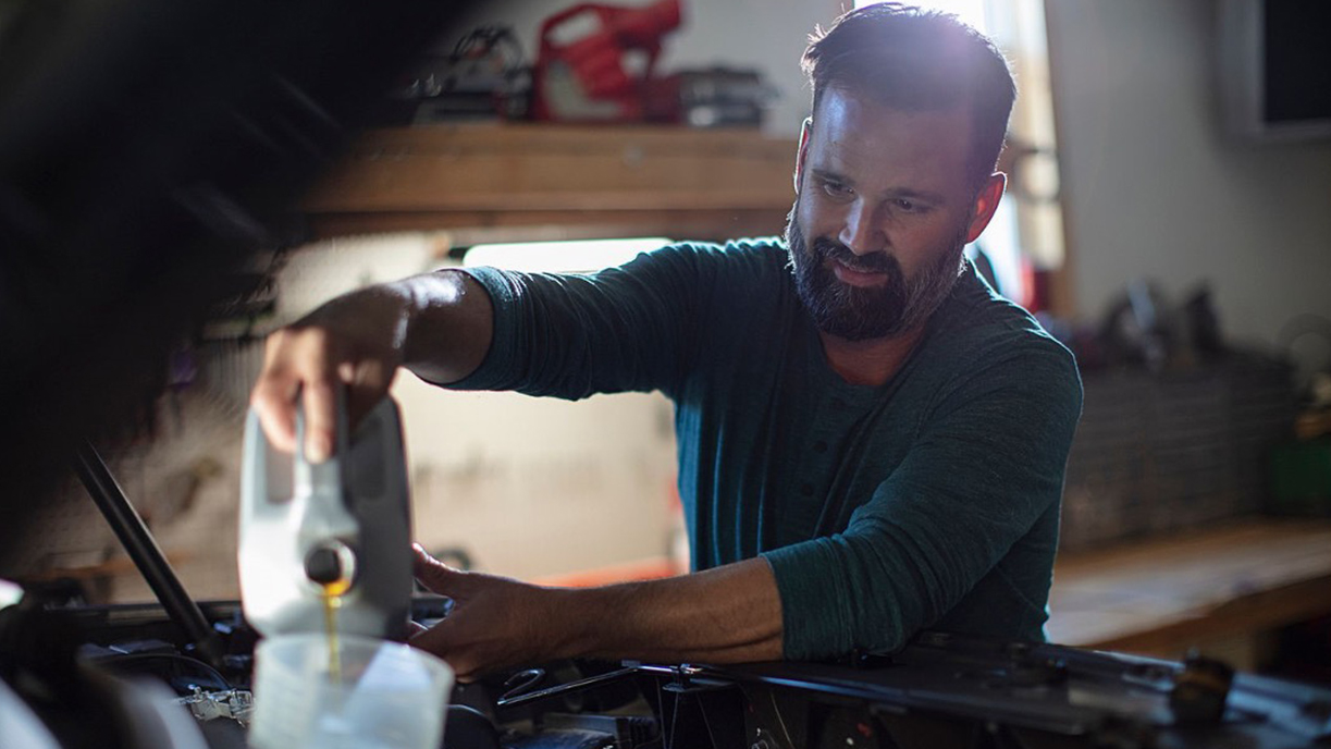 Mechanic pouring oil into car