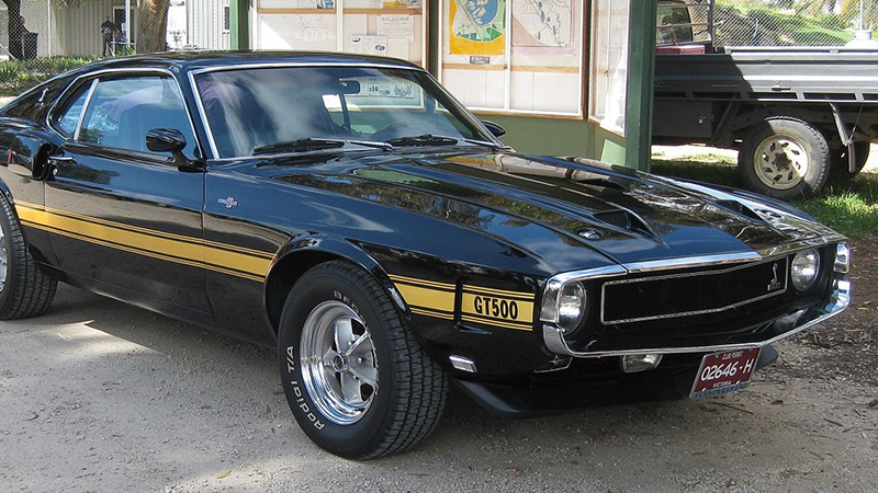 A black Shelby GT sits at a gas station.