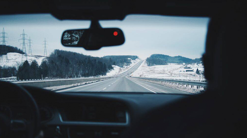Two people in a car on a wintery road.