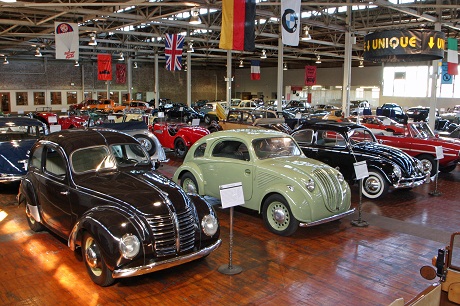 Flags hanging from the ceiling identify country of origin of cars. Photo credit: Lane Motor Museum.