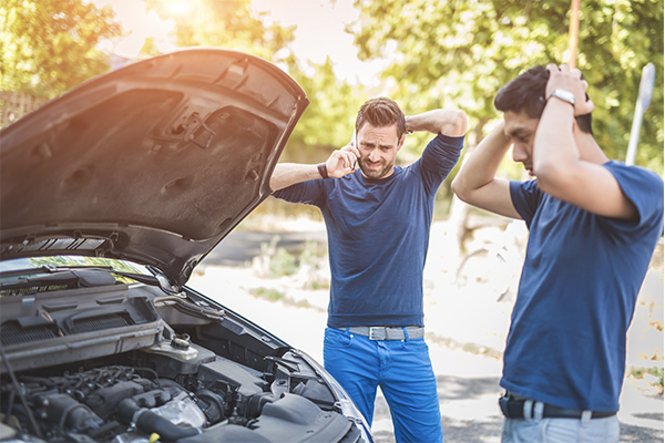 two men standing by a broken down car