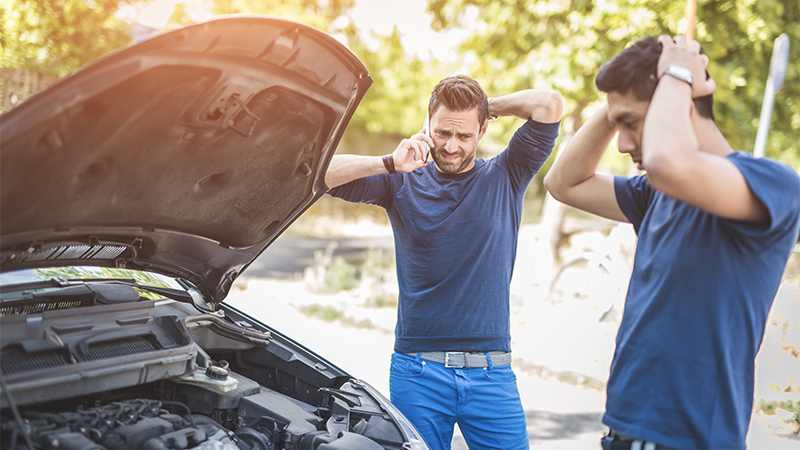 two men standing by a broken down car