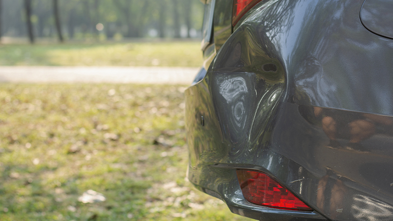 a large dent in the right rear corner of a gray bumper