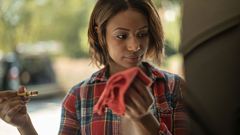 a woman checks the oil level on the dipstick
