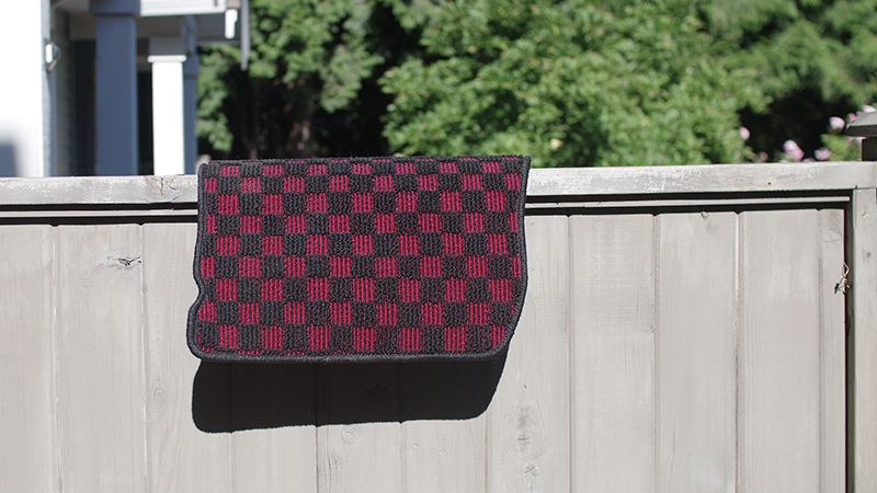 car mat hanging on a fence to dry