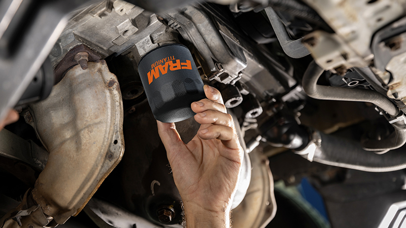 a hand installing a black FRAM filter