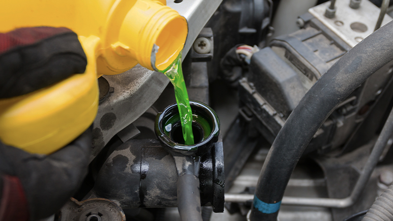 a close-up of green coolant being poured into the radiator neck