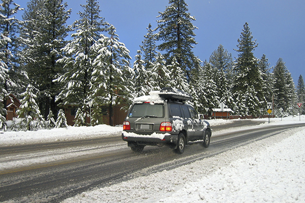 An SUV drives down a snow-lined street