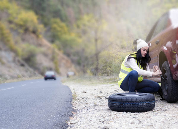 woman changing tire on the side of the road