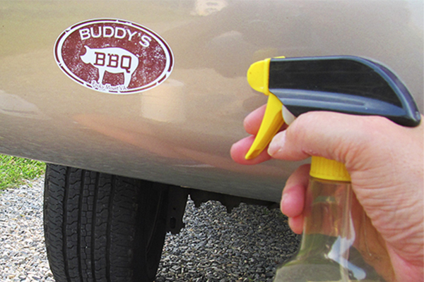 spraying Goo Gone on an old bumper sticker
